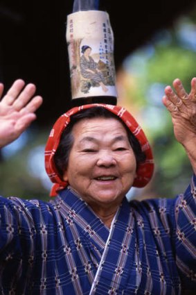 Life force: an elderly Okinawan woman dances with bottle on head.