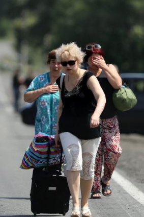 Fleeing residents of Shakhtersk carry their belongings in bags as they run to waiting cars on the outskirts of the city during heavy shelling.