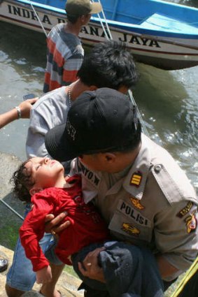 An Indonesian policeman carries an exhausted young boy following more rescues from the sunken asylum seeker boat off West Java.