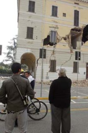 People gather on a street in front of the damaged Town Hall building on Sant' Agostino near Ferrara.