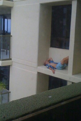 A schoolie sleeps on building ledge on the Gold Coast.