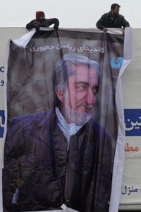 Undaunted: Afghan workers install a campaign banner of Abdullah Abdullah in Kabul.