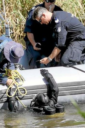 A police diver hands over an object found in a search of the Yarra River in March related to Dimitrios Belias' death.