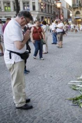 A man prays near flowers and toys after attending a silent march of remembrance in Amsterdam.