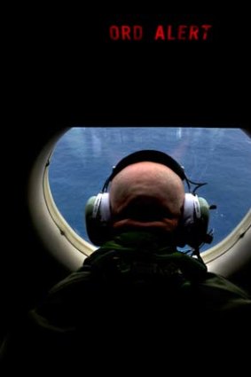 Eyes peeled: Warrant Officer Michael Wright keeps watch from an RAAF aircraft.