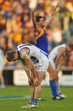Leigh Adams of the Kangaroos looks dejected as Dean Cox of the Eagles celebrates victory at Blundstone Arena in Hobart.
