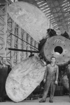 Dwarfed but standing tall: 1950s dockyard tradesmen pose with a single-mould brass propeller.