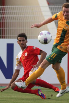 Heat is on: Socceroo David Carney tackles Amad Ali Sulaiman al-Hosni in a scorching Oman.