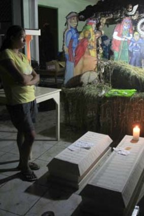 A woman stands next to the coffin of her child and other typhoon victims who drowned in flash floods in the Philippines.