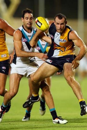Shannon Hurn of the Eagles kicks under pressure from Matthew Broadbent of the Power.