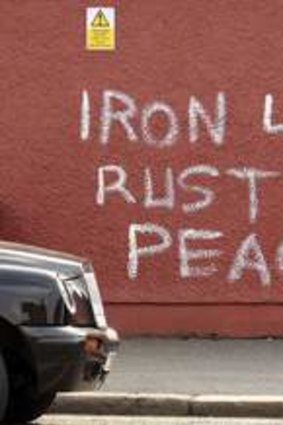 A man passes graffiti daubed on a wall referring to the death of former prime minister Margaret Thatcher.