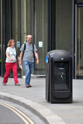 Pedestrians walk past one of the high-tech rubbish bins in London that are capable of collecting smartphone data.