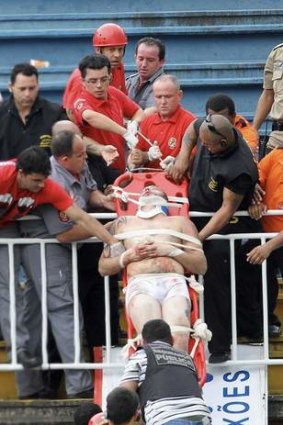 Paramedics use a stretcher to carry an injured Atletico Paranaense fan.