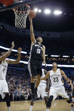 San Antonio Spurs guard Tony Parker drives to the basket between New Orleans Pelicans duo Alexis Ajinca and Anthony Davis.