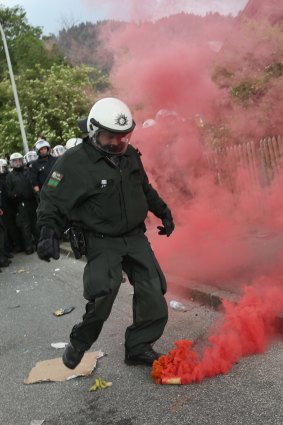 A policeman kicks away a smoke bomb during scuffles that involved tear gas and pepper spray during a march by anti-G7 protesters in Germany.