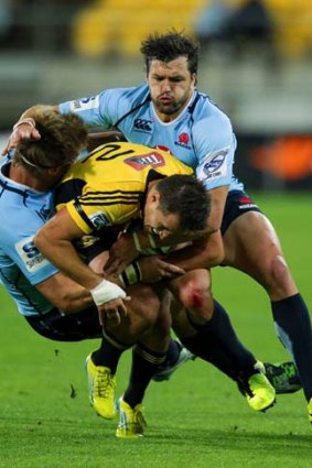 Tim Bateman of the Hurricanes is tackled by Pat McCutcheon (L) and Adam Ashley-Cooper of the Waratahs.