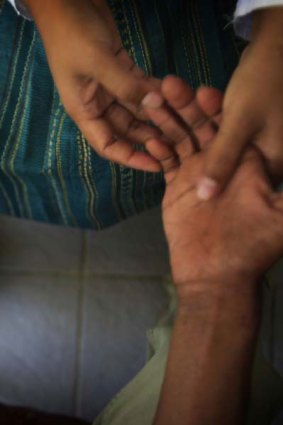 A health worker massages the hand of a patient that has begun to claw.