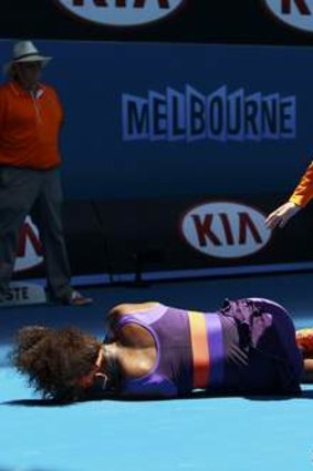 An offical stands over Serena Williams after she fell heavily.