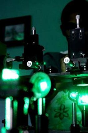 A research scholar experiments with laser rays in a lab.