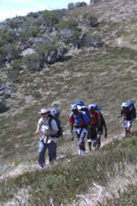 The group of young people trek down a mountain.