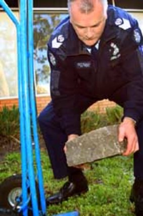Senior Sergeant Gary Maddern with the rock that was thrown from the bridge.