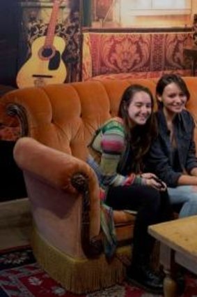 Visitors pose for a photograph on a couch at the Central Perk.