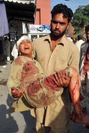 Bloody vengeance:  A Pakistani  carries an injured blast victim to  hospital after the  Shabqadar  bomb attack.