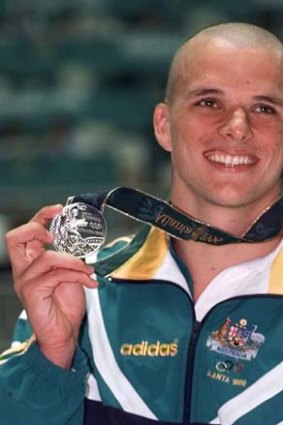 Claiming silver in Atlana: Scott Miller holds up his medal after coming second in the men's 100 meter butterfly at the 1996 Summer Olympics.