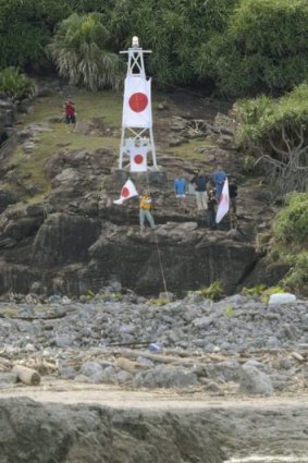 Members of a Japanese nationalist group raise Japanese flags as they land on Uotsuri island, part of the disputed islands in the East China Sea.
