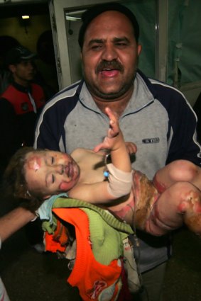 A man carries his wounded  child into a Gaza hospital.