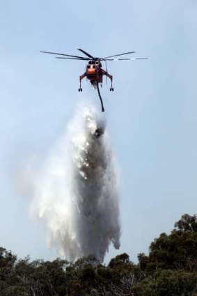 A water-bombing helicopter dumps water over an uncontrolled bushfire near Violet Town.