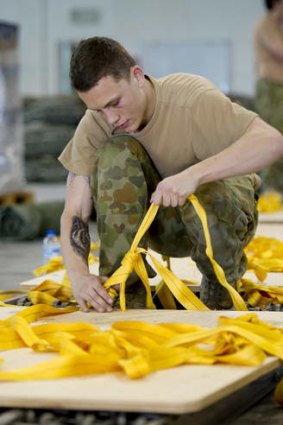 Private Toby Rogalski, a Parachute Rigger with 176 Air Dispatch Squadron, prepares a skid board for an airdrop bundle of humanitarian aid.