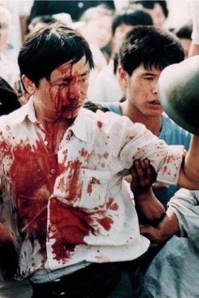 A blood-covered protester holds a soldier's helmet following clashes on Tiananmen Square.