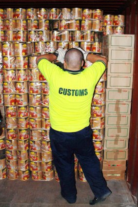 Cans of worms: An Australian Customs officer with some of the tomato cans containing ecstasy tablets in Melbourne in 2008.