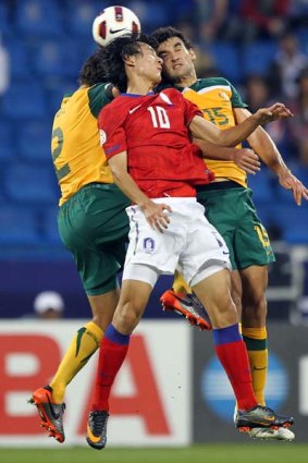 Australia's defender Lucas Neill (left) and midfielder Mile Jedinak (right) contest the ball with South Korea's forward Ji Dong-Won.