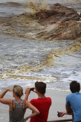 Tourists look toward polluted water in Coolum, Queensland, after up to 100 tonnes of fuel were believed to have spilled from the Pacific Adventurer.