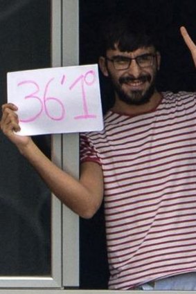 A man in one of the hospital wards cleared for patients under observation at Carlos III hospital in Madrid waves a banner on Saturday giving his temperature as 36.1 degrees - meaning he has no fever.