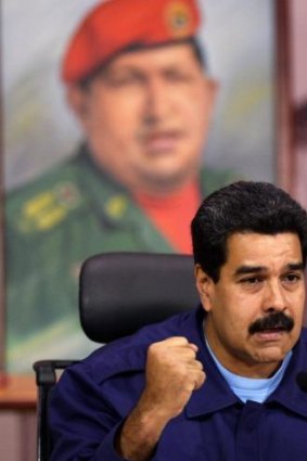 Defiant: Venezuelan President Nicolas Maduro speaks to the media in front of a portrait of his dead predecessor, Hugo Chavez.