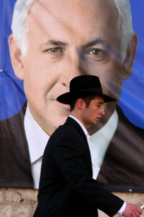 An Israeli Orthodox Jew walks past an election campaign poster of Israel's former prime minister Benjamin Netanyahu.