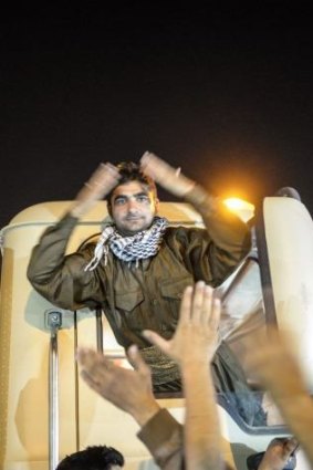 An Iraqi Kurdish fighter salutes Turkish Kurds who turned out to greet the convoy.