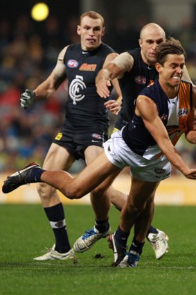Carlton's Chris Judd is unable to prevent West Coast's Tom Swift from firing off a handball.