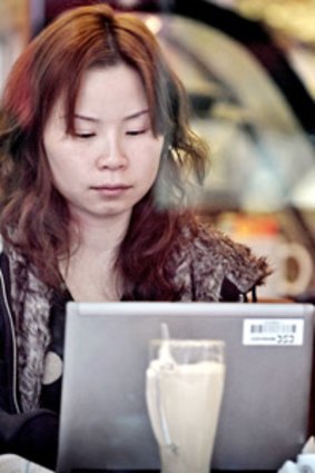 A woman surfs the internet on a laptop using the wi-fi connection of a cafe in Shanghai... China wants telcos to dob on clients who trade secrets.  Photo: AFP/ Philippe Lopez