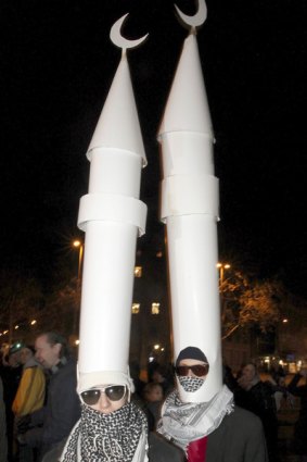Two demonstrators wear minarets made from paper on their heads to protest against the results of a vote in Switzerland.