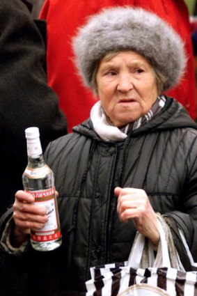 An elderly woman sells a bottle of vodka on a street in Moscow.
