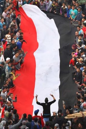 Protestors hold a giant Egyptian flag aloft in Tahrir Square on November 26, 2011 ... two days before the first round of Egypt’s first democratic parliamentary elections in 60 years begins.