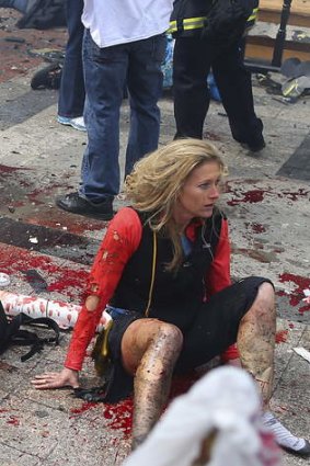 A woman sits stunned moments after the blasts