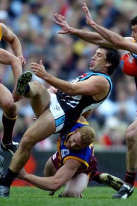 Port Adelaide's Roger James kicks into Brisbane's Nigel Lappin as he is dragged down by Michael Voss during the 2004 grand final. The Lions entered the game with about 36 hours less preparation than Port.
