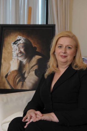 Suha Arafat poses next to a portrait of her late husband Yasser Arafat at her home in Malta.