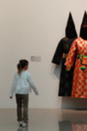 Young girl walks past a work titled <em>HHH</em> by artist Fiona Foley at the NGA in Canberra.