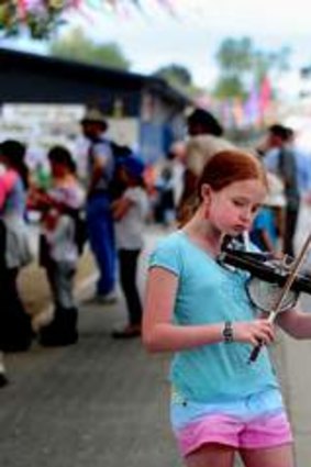 Claire Doherty, 11, busks at the National Folk Festival, Canberra with her Stroh Violin.